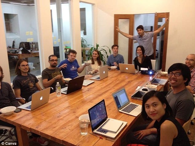 A conference table with multiple people working on their laptop, Canva team at work. 