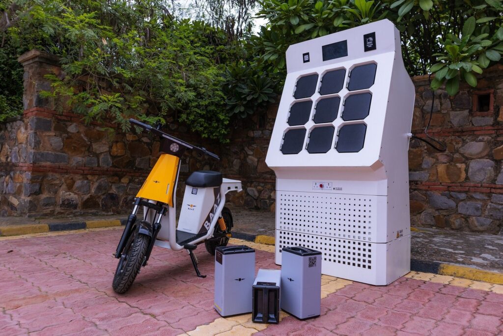 A base bikes e-scooter standing next to a battery swapping station (Baaz Swap)